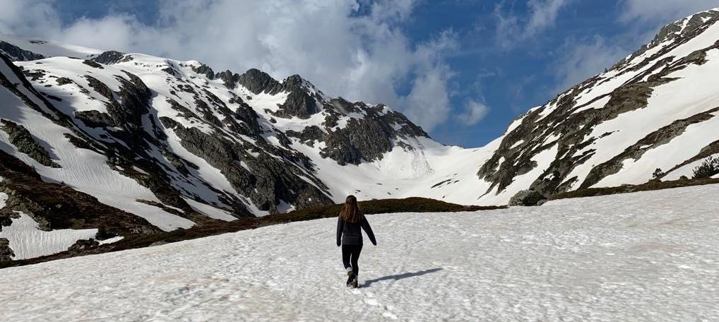 woman walking on a snowy mountian top under a blue sky